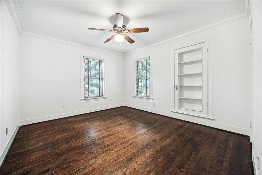 Second secondary bedroom with built-in shelving and windows overlooking the greenery.