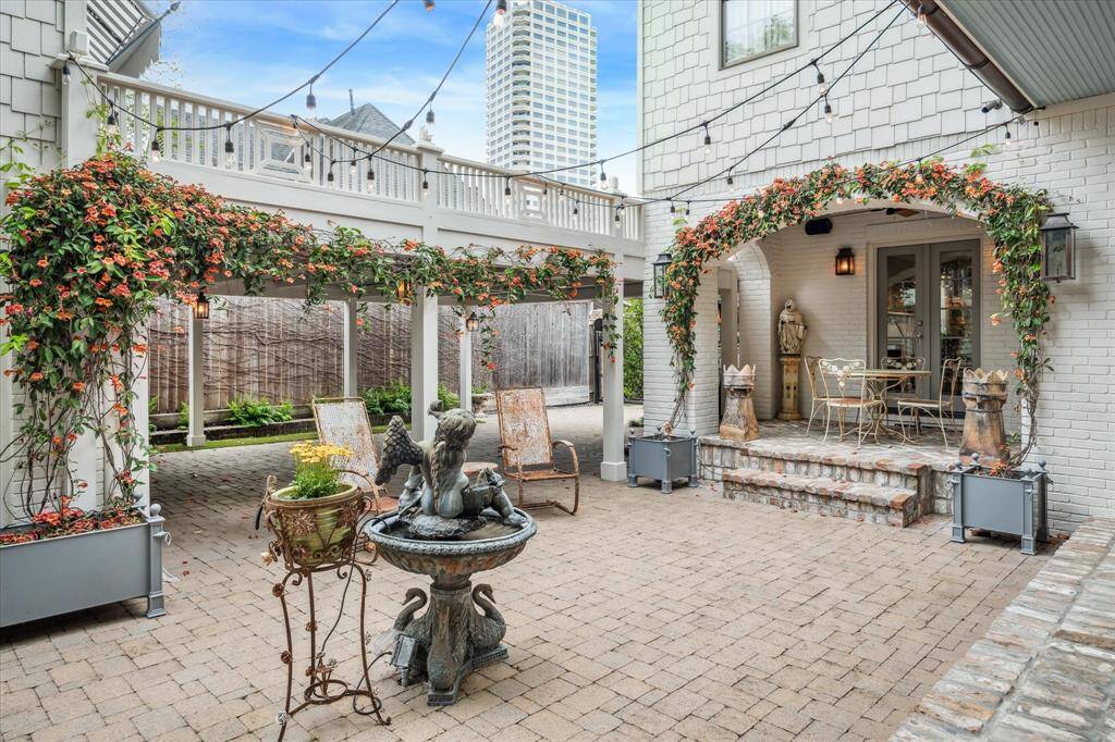 French doors lead to the beautifully hardscaped backyard, where architectural details and greenery combine for timeless charm.