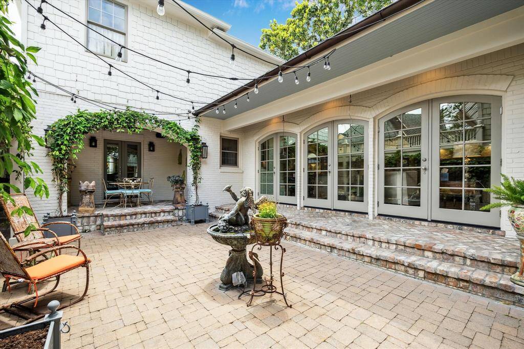 Step into a serene courtyard with charming brick pavers, string lights, and lush greenery—ideal for alfresco dining or enjoying your morning coffee.