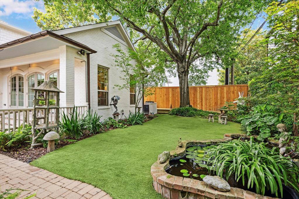 The backyard features a tranquil koi pond surrounded by mature landscaping, creating a peaceful sanctuary shaded by a magnificent tree.