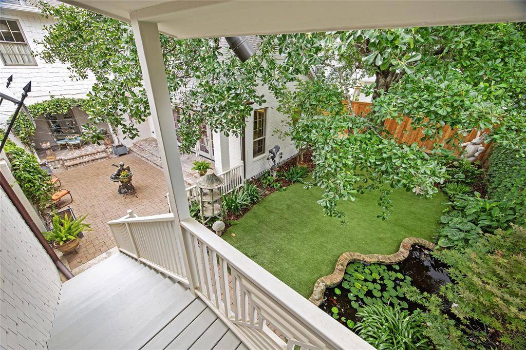 From the top of the stairs, enjoy a bird’s-eye view of the lush backyard and brick courtyard—a perfect perspective of this inviting outdoor haven.