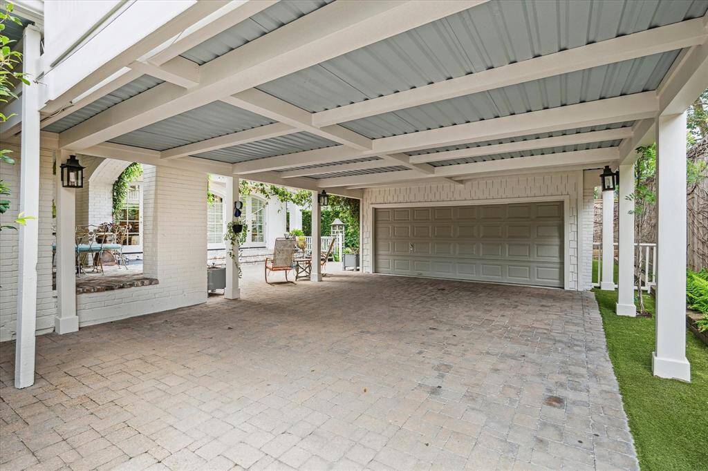 A spacious covered carport offers additional parking and leads directly to the two-car garage and quarters above.