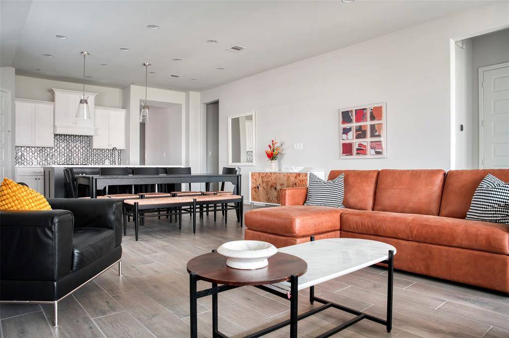 This modern living space features an open layout with a stylish kitchen, spacious dining area, and cozy seating. The room is bright and inviting, with contemporary furnishings and neutral tones that complement the sleek design.