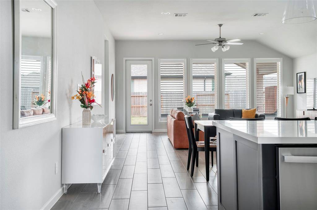 This open-concept living area features modern design with large windows for ample natural light, sleek flooring, and a stylish kitchen island. The space is perfect for entertaining and offers a seamless flow to the outdoor area.