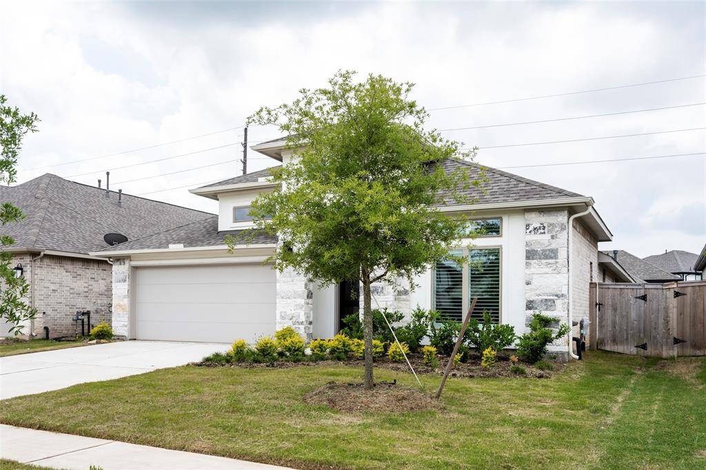 Charming single-story home with a modern exterior, featuring a two-car garage and well-maintained landscaping. The front yard includes a small tree and neatly arranged shrubs, enhancing curb appeal. Located in a quiet neighborhood with easy access to amenities.