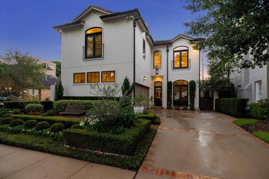 Elegant stucco exterior with Juliet balconies, tile roof and manicured front gardens on a beautifully landscaped West U lot.