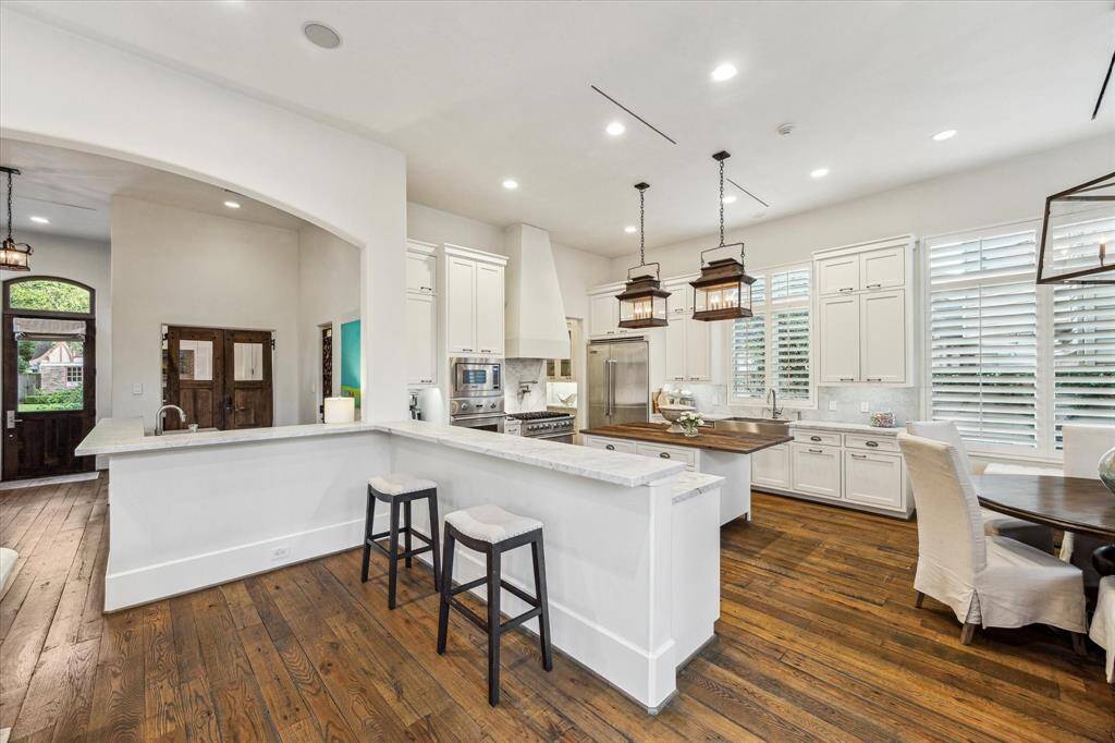 Bright kitchen with marble counters, custom cabinetry, and breakfast seating—open to main living and foyer.
