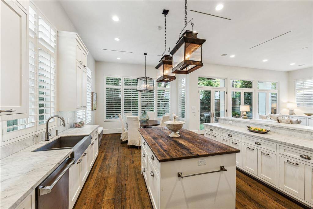 Chef’s kitchen with Viking appliances, Carrera marble counters, wood island, and abundant natural light from surrounding windows.