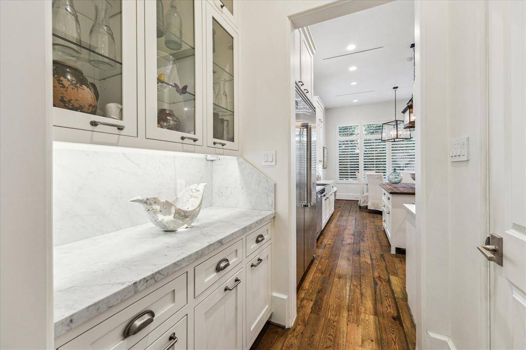 Butler’s pantry with marble counters and glass-front cabinetry, connecting kitchen and formal dining for seamless service.
