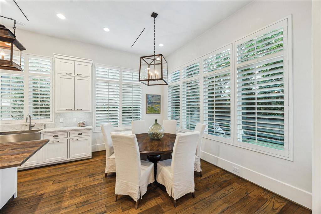 Breakfast room wrapped in windows with plantation shutters—flooded with natural light and open to the kitchen.