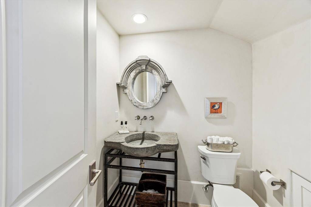 Powder room with custom stone sink, designer mirror, and Venetian plaster walls.