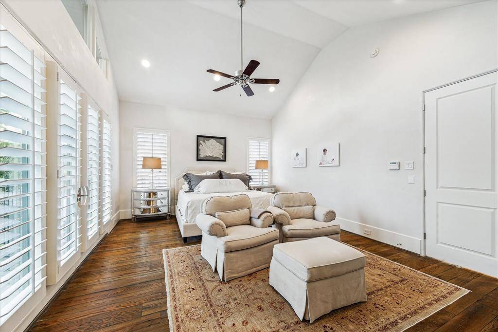 Primary bedroom with vaulted ceiling, sitting area, and wall of windows with access to a private balcony.