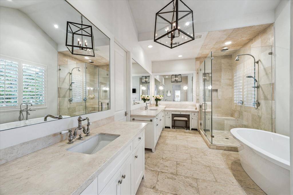 Spa-like primary bath with dual vanities, walk-in shower, soaking tub, and dedicated vanity.