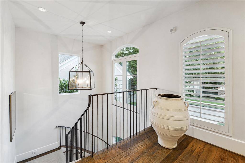 Light-filled stair landing with iron railings and picture windows—an elegant transition space with views to the front and side yards.