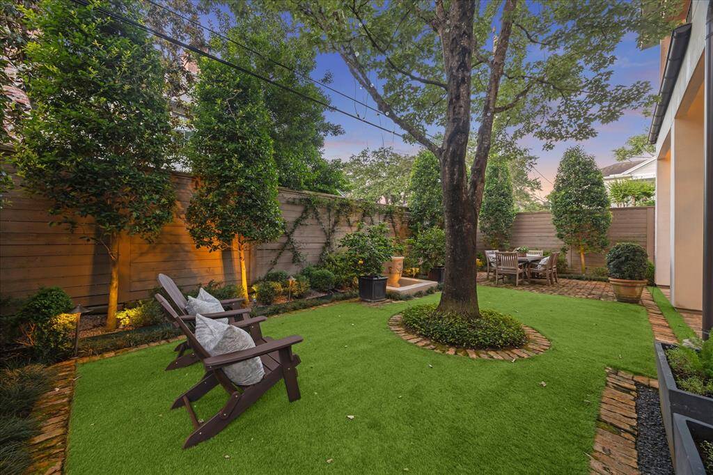 Private outdoor oasis with turf lawn, brick paths, and dining patio—ideal for entertaining or relaxing under mature trees.