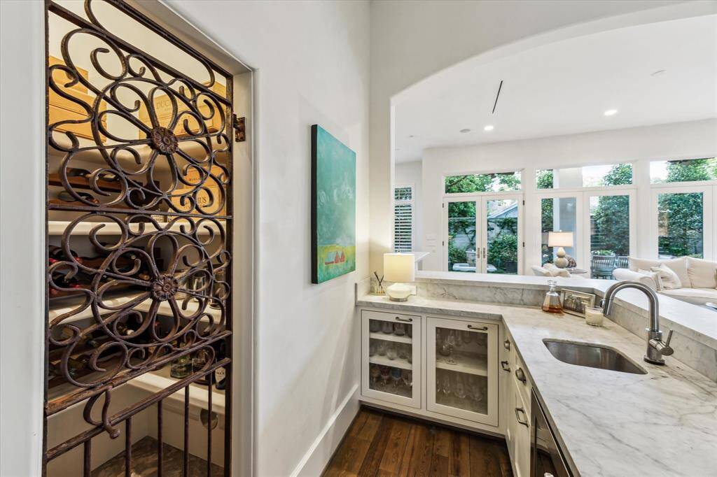 Wet bar with marble counters and wine room, positioned between kitchen and living for seamless entertaining; framed by natural light and courtyard views.