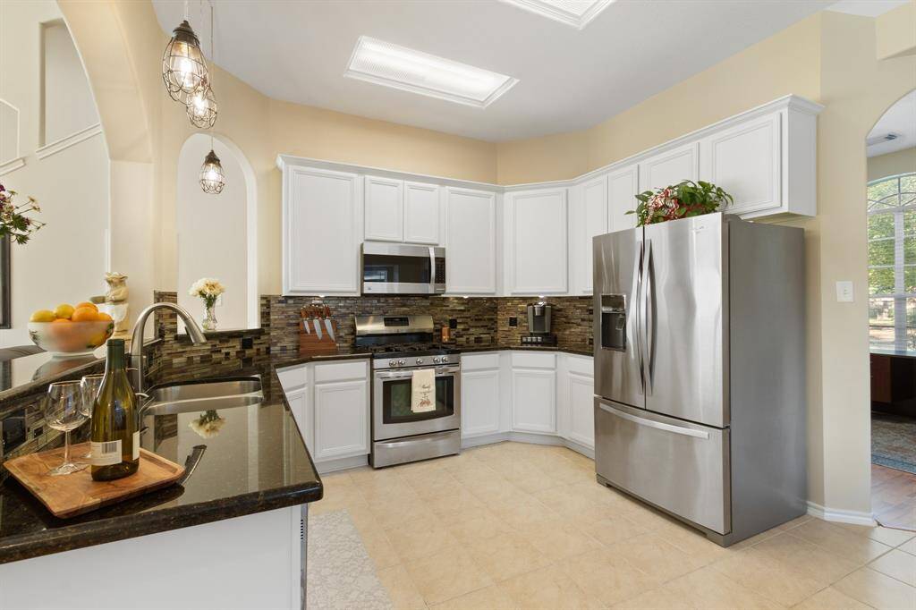 The spacious living area features wood laminate floors, high ceilings, ceiling fan and convenient door access to the back patio area.