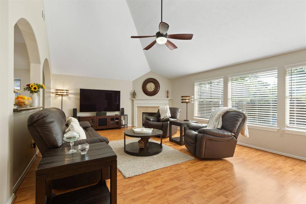 This room is bright and spacious, featuring elegant coffered ceilings, stylish wood laminate flooring, a ceiling fan for comfort, and a wall of windows complete with charming bench seating.
