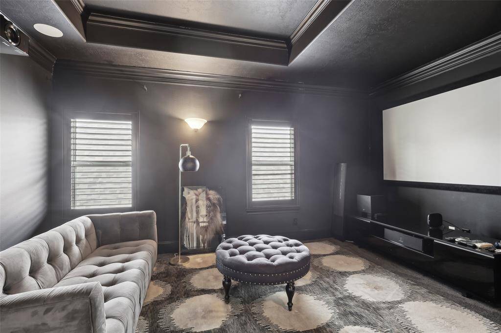 This photo showcases a stylish home theater room with dark walls and ceiling, featuring a large screen, and a cozy ambiance, perfect for movie nights.
