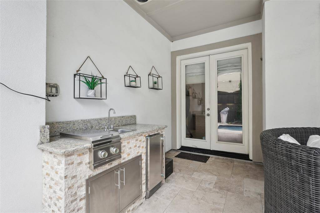 This photo showcases an elegant outdoor kitchen area featuring a built-in grill, granite countertops, and stainless steel appliances.