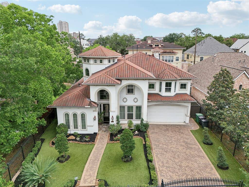 Red-tiled roof and white stucco exterior. The property is surrounded by mature trees and is situated in a well-established neighborhood.