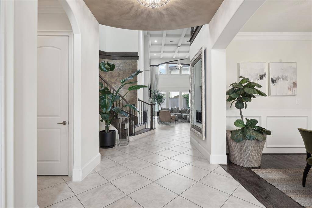 This photo showcases a bright and elegant entryway with tiled flooring leading into a spacious living area. The high ceilings and large windows allow for plenty of natural light.