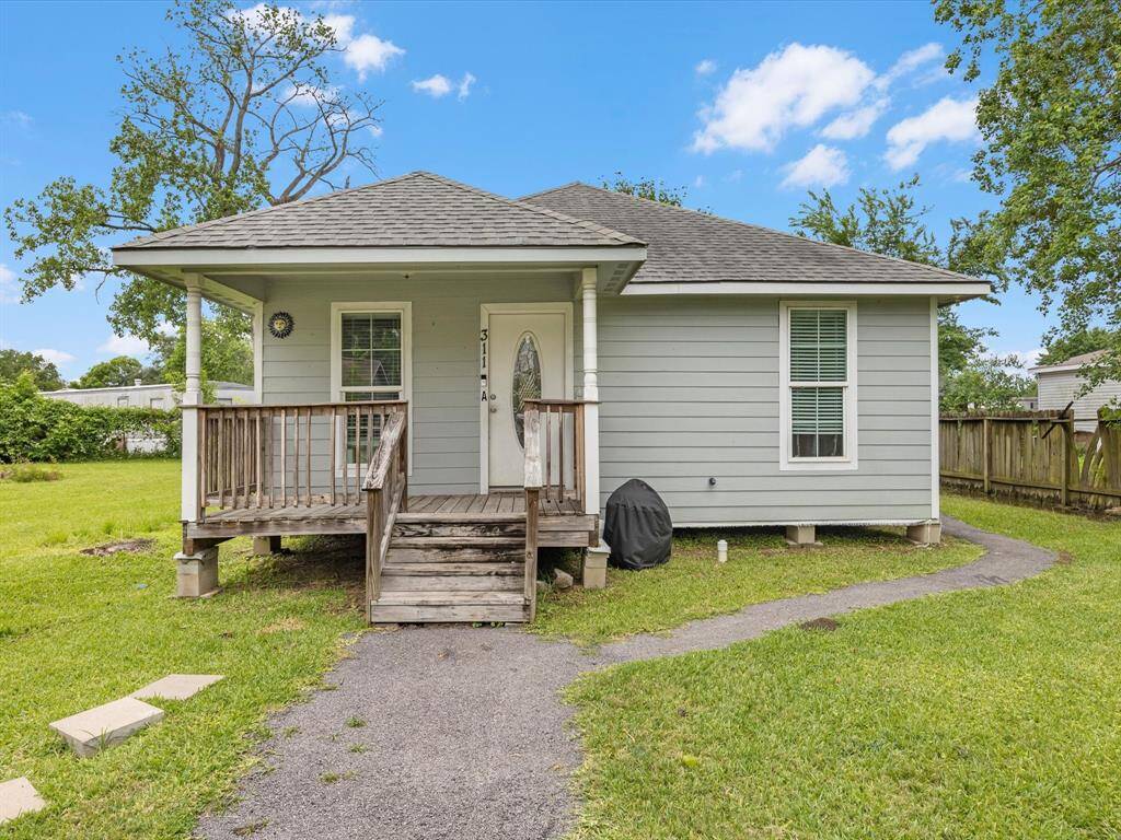 Second single-story home with a welcoming front porch, set in a spacious yard. Ideal for cozy living with potential for outdoor activities.
