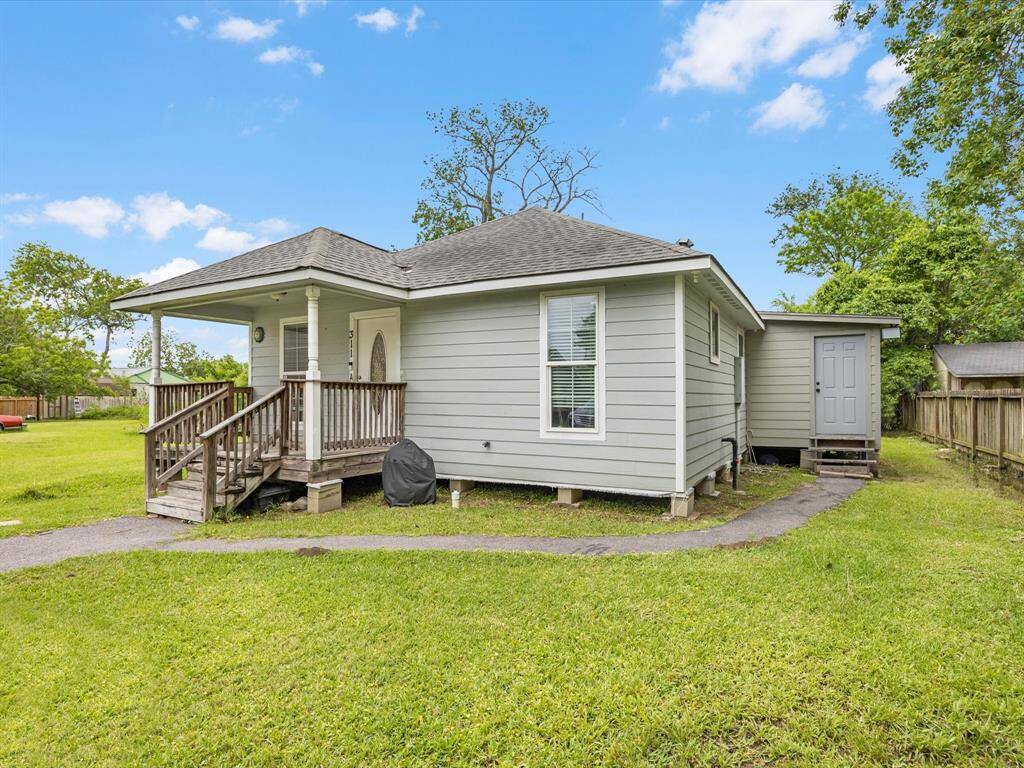 Second single-story home with a welcoming front porch, set in a spacious yard. Ideal for cozy living with potential for outdoor activities.