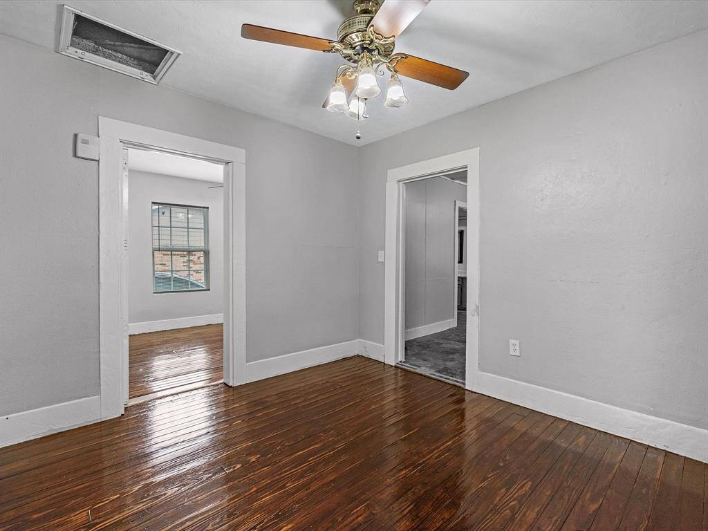 Freshly painted dinning room with polished hardwood floors and a ceiling fan. It features two doorways, leading to Kitchen and second room.