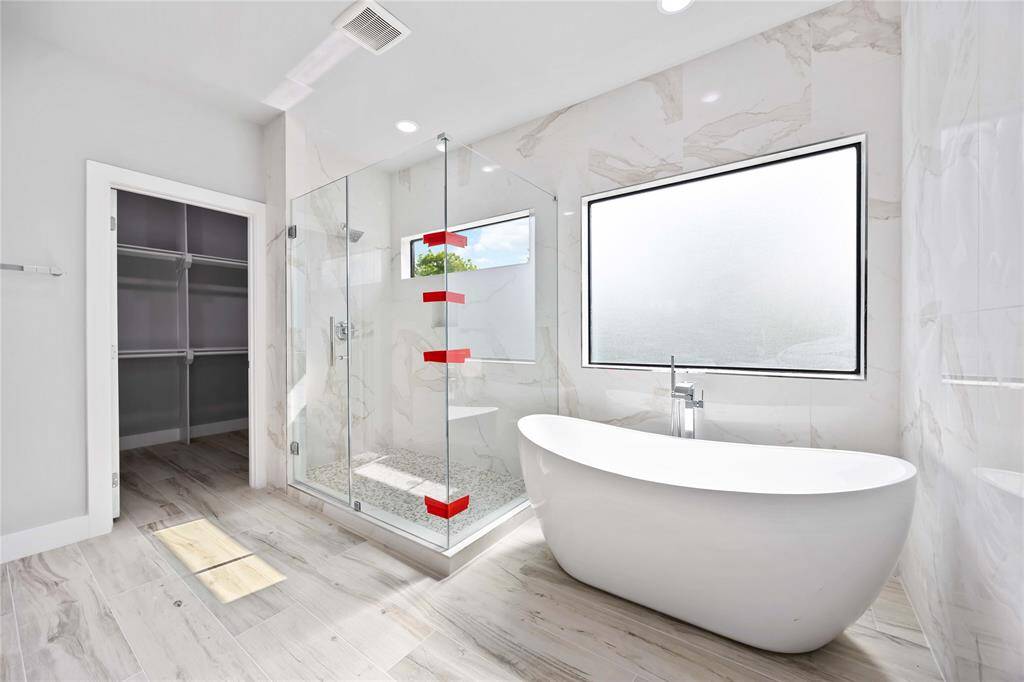 Indulent primary bath retreat with sculptural freestanding tub, luxurious glass-enclosed shower, and designer dual vanities creating a personal spa experience