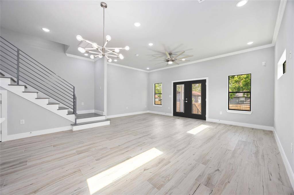 Dramatic open concept living space with elevated ceilings, expansive windows capturing abundant daylight, and effortless connection to outdoor entertaining area