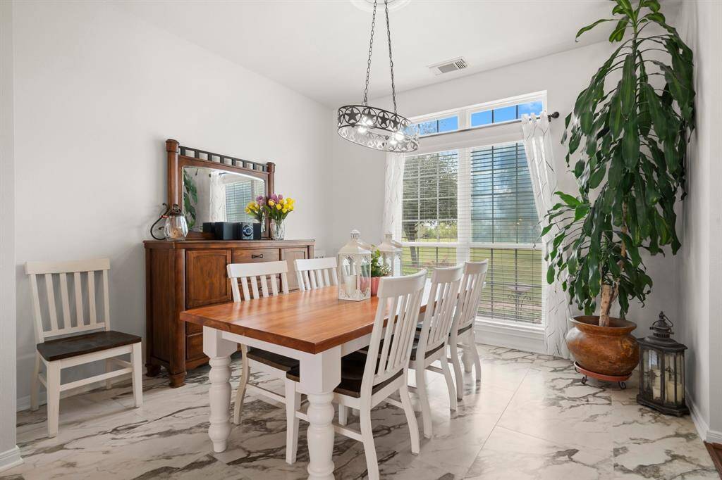 This bright and inviting dining area offers a comfortable space for family meals and entertaining, featuring ample natural light and stylish accents.
