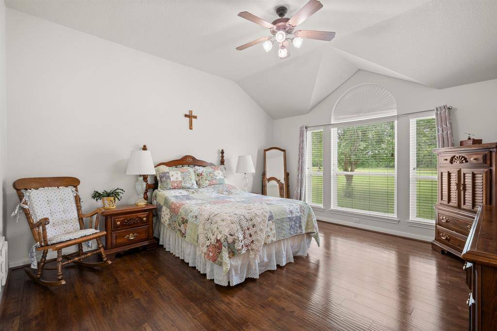 This comfortable bedroom boasts an open feel thanks to the vaulted ceiling and abundant natural light from the expansive windows. It's a peaceful haven designed for relaxation.