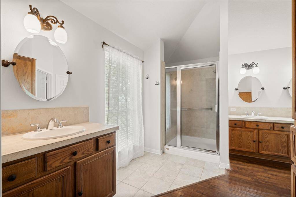 This bathroom offers the convenience of double vanities, providing ample space for getting ready. A separate shower enhances the functionality of this well-appointed space.