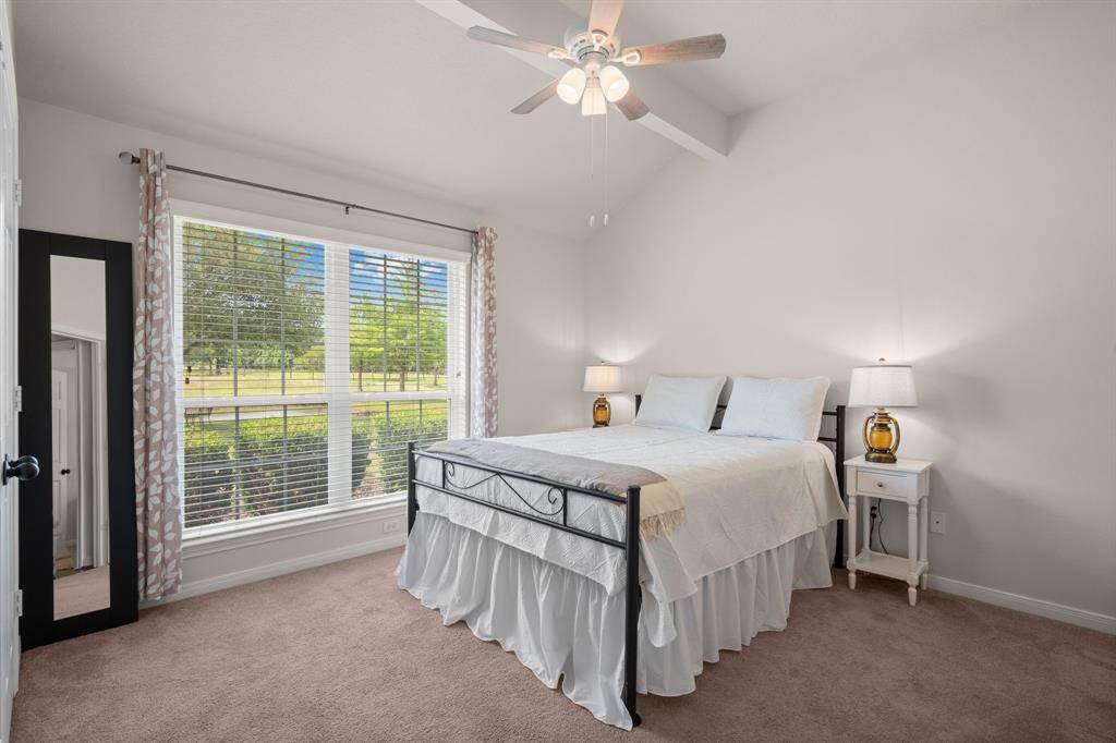 Enjoy a tranquil atmosphere in this bedroom, featuring a vaulted ceiling and a large window that brings the beauty of the backyard indoors.