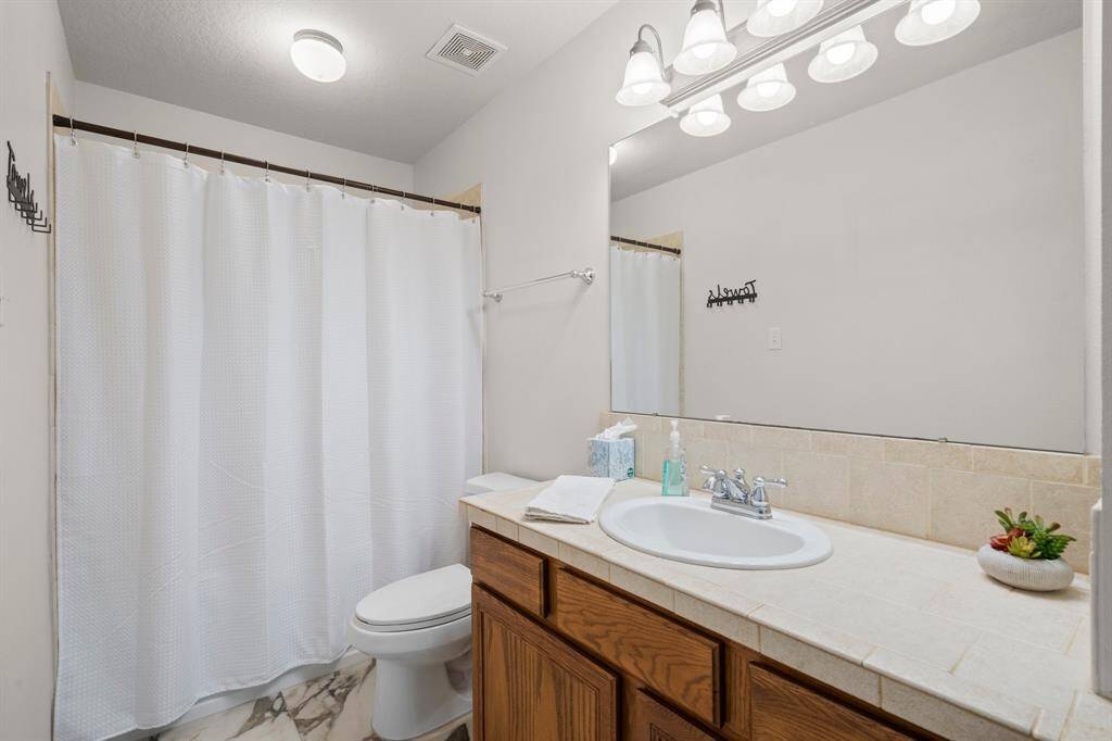 This bathroom provides all the essentials, including a shower/tub combination and a functional vanity.