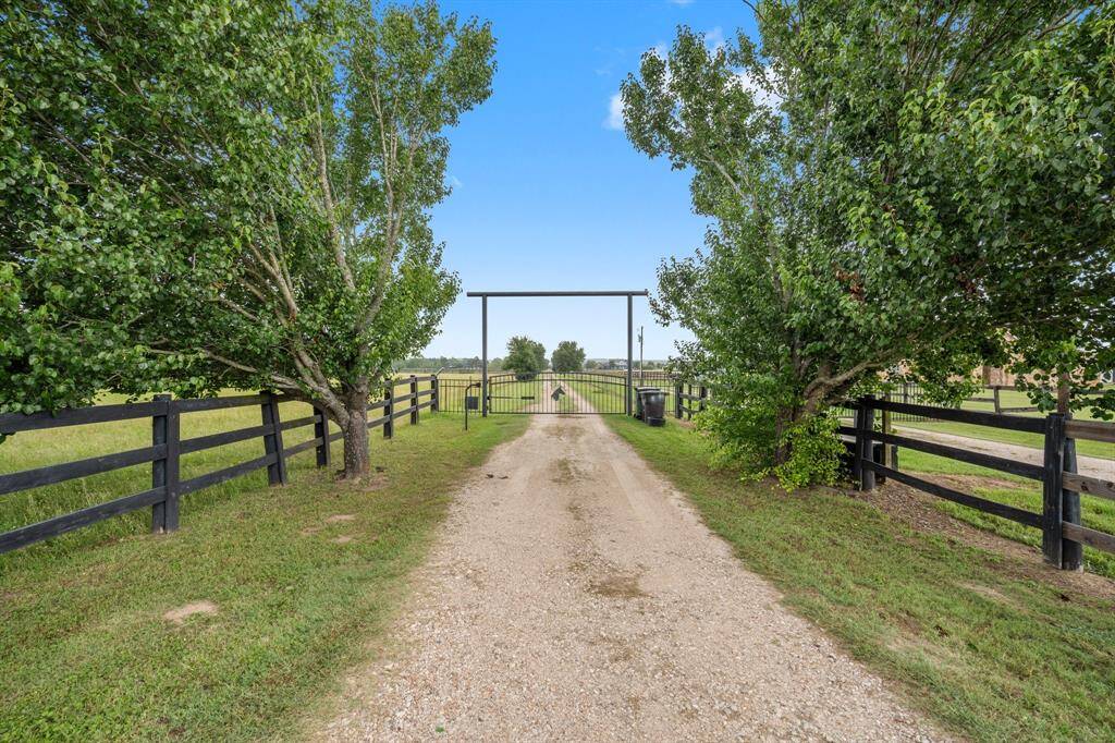 Enjoy the peace and privacy offered by this secluded property. The gated entrance and long driveway are framed by mature trees and fencing, creating a tranquil and picturesque setting.
