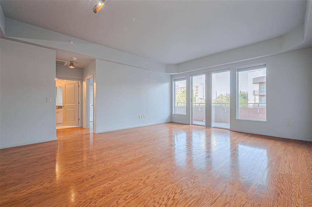 Bright and spacious living area with hardwood floors, large windows for natural light, and access to a balcony. Ideal for a modern, open-concept design.