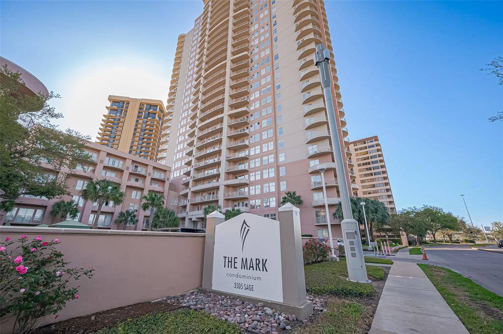 Modern high-rise condominium complex with well-maintained landscaping. Features a prominent entrance sign and offers urban living with nearby amenities.