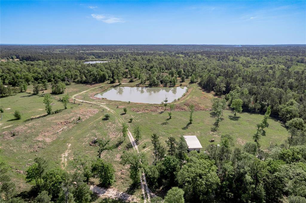 2 acre stocked pond is approximately 3/4 mi from the front gate. A larger 9 acre stocked lake you can see just beyond the trees on the top left. There is a covered storage area on the bottom right.