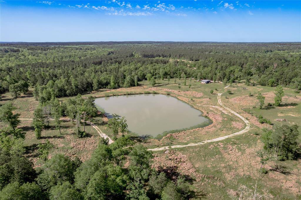 Center section of property looking SouthWest, the 2 acre pond with the storage area just beyond the pond on the left. The road to the right of the storage area goes back to the front gate.