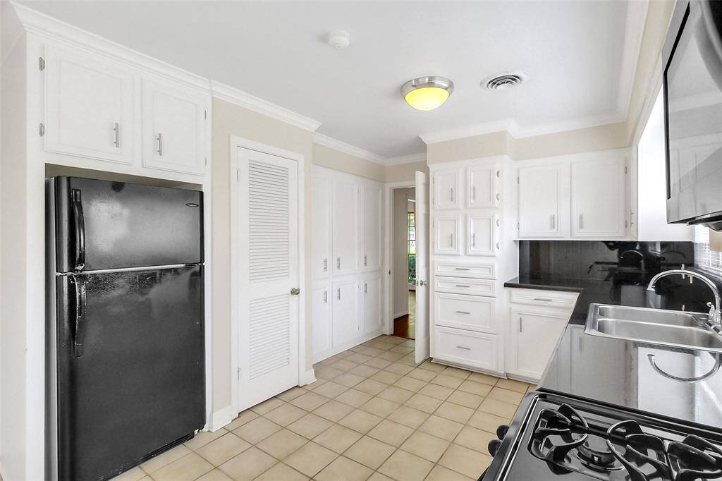 Just across are a black refrigerator/freezer, pantry, and then a wall of extra cabinet storage.