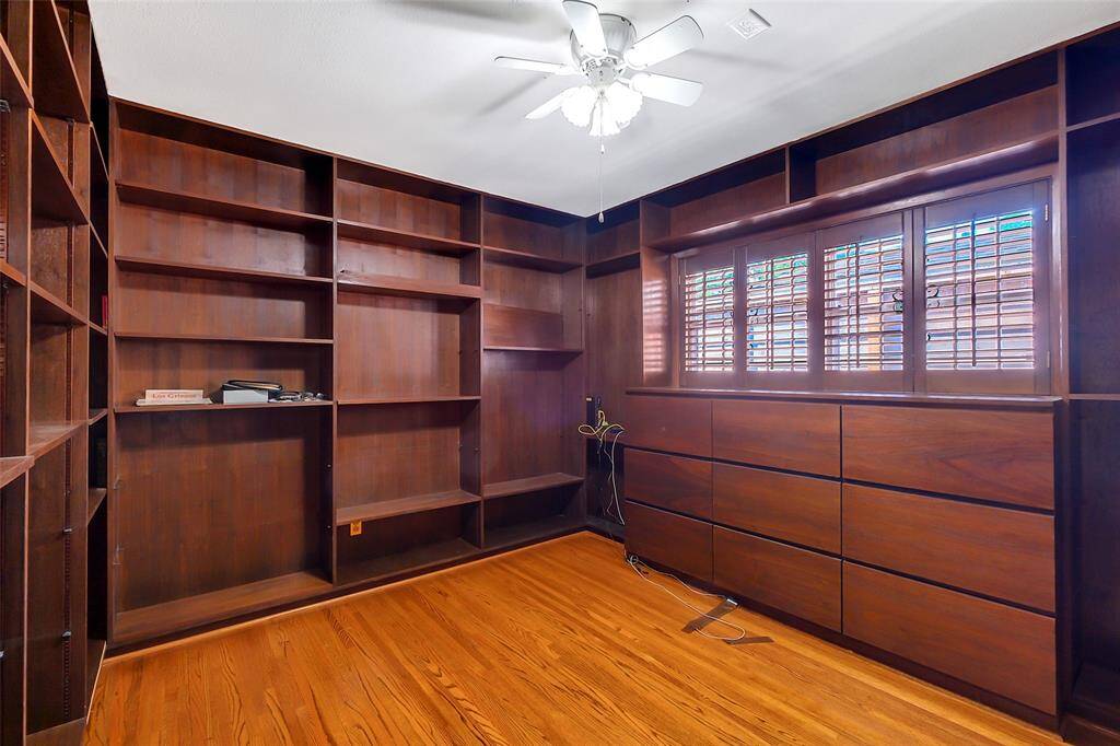 The middle bedroom had been turned into a study with dark paneling throughout and floor to ceiling bookcases and shelving for books and collectibles. Below the window with plantation shutters is a set of six large built-in drawers.