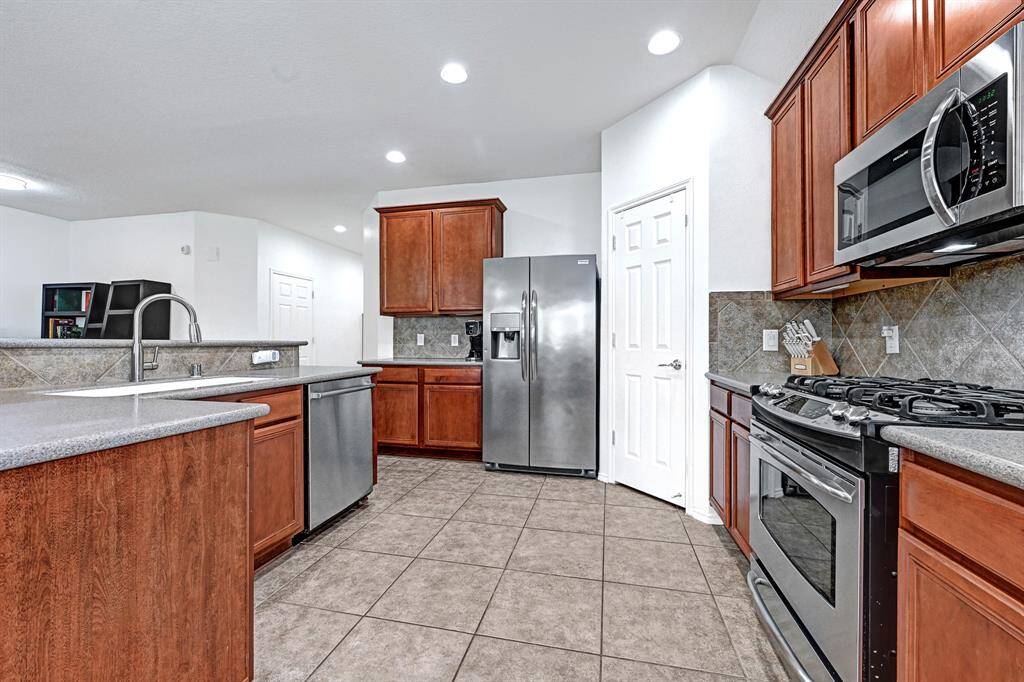 The kitchen boasts stainless steel appliances, pantry, tiled backsplash, and plenty of prep-space for the home cook.