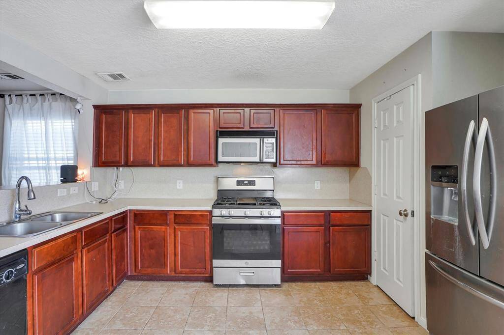 Functional kitchen with ample cabinet storage, updated appliances, and a view into the backyard.