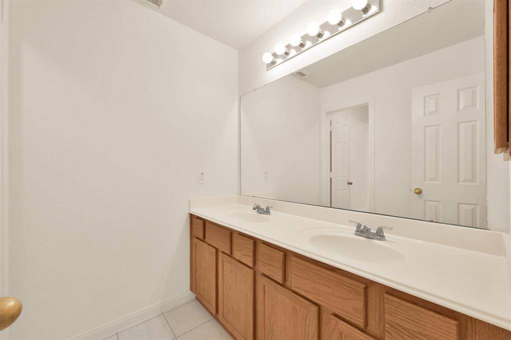 Secondary full bathroom with double sinks. Shower/tub and toilet through the open door. New ceramic tile in all bathrooms 2025.