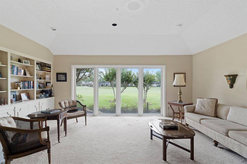 Step inside to a spacious living room filled with natural light from a wall of windows showcasing panoramic golf course views.