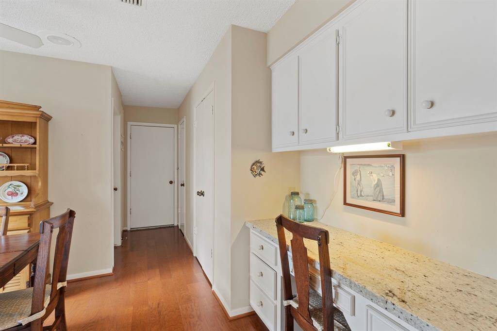 A built-in desk tucked into the breakfast area offers a practical workspace, complete with drawers, storage cabinets, and under-cabinet lighting—ideal for a home office or organizing daily essentials.