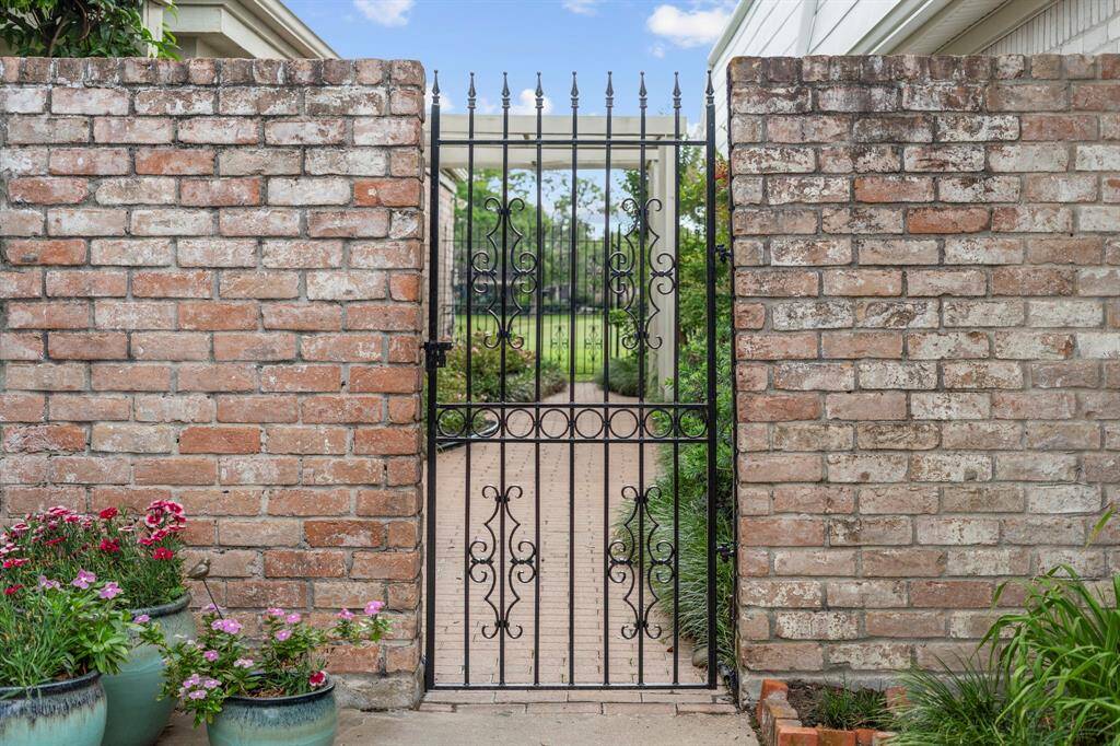 Tucked just beyond a secure wrought-iron gate, this charming side courtyard offers a serene escape. Mature plantings and climbing ivy soften the classic brick, while the gated entrance adds both security and an old-world touch of charm.