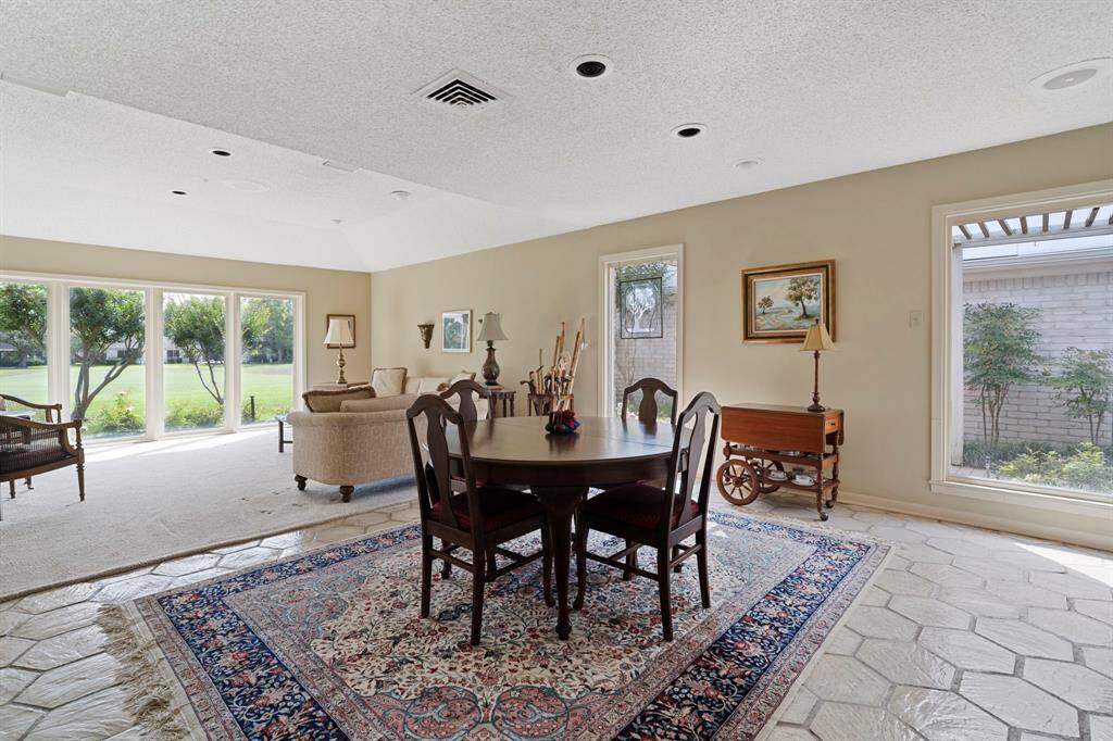 The open-concept dining and living area is bathed in natural light from expansive windows that frame beautiful views. Neutral finishes provide a versatile backdrop to suit any style of décor, while recessed lighting adds a warm, modern touch to the space.